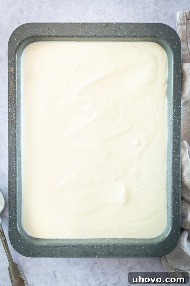 overhead view of the creamy filling evenly spread over the cooled pecan crust in a baking pan.