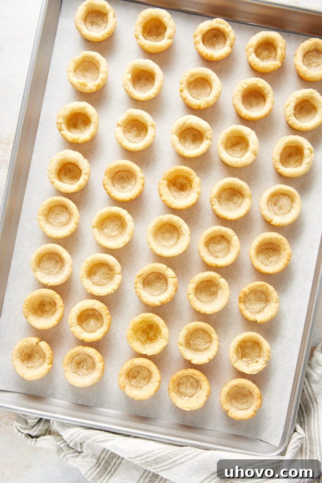 Baked cream cheese pie crusts on a baking sheet lined with parchment paper