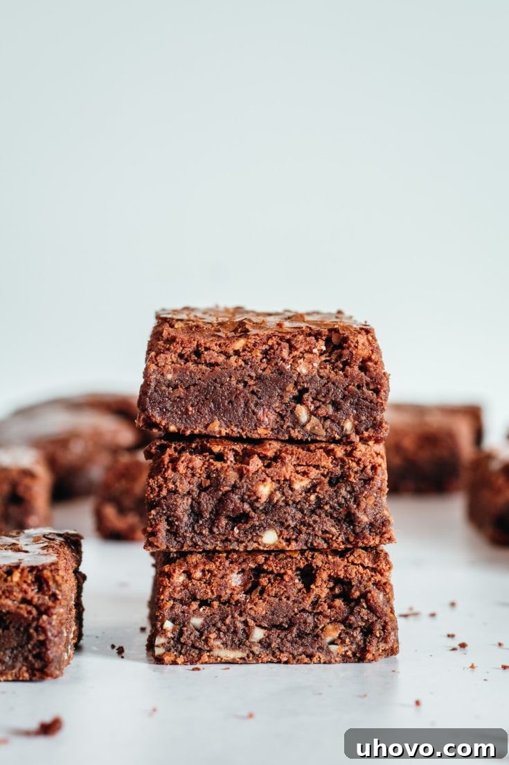 Stack of 3 Supernatural Brownies, adorned with chopped nuts, showcasing their rich texture and flaky top