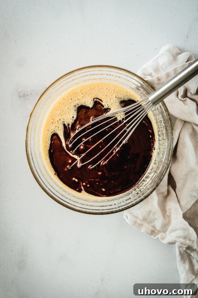 Overhead view of the smooth, melted butter and chocolate mixture in a mixing bowl, ready to be incorporated into the brownie batter