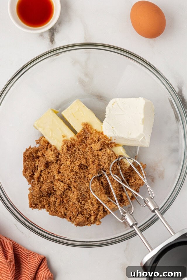 overhead view of butter, cream cheese, and brown sugar in a glass mixing bowl