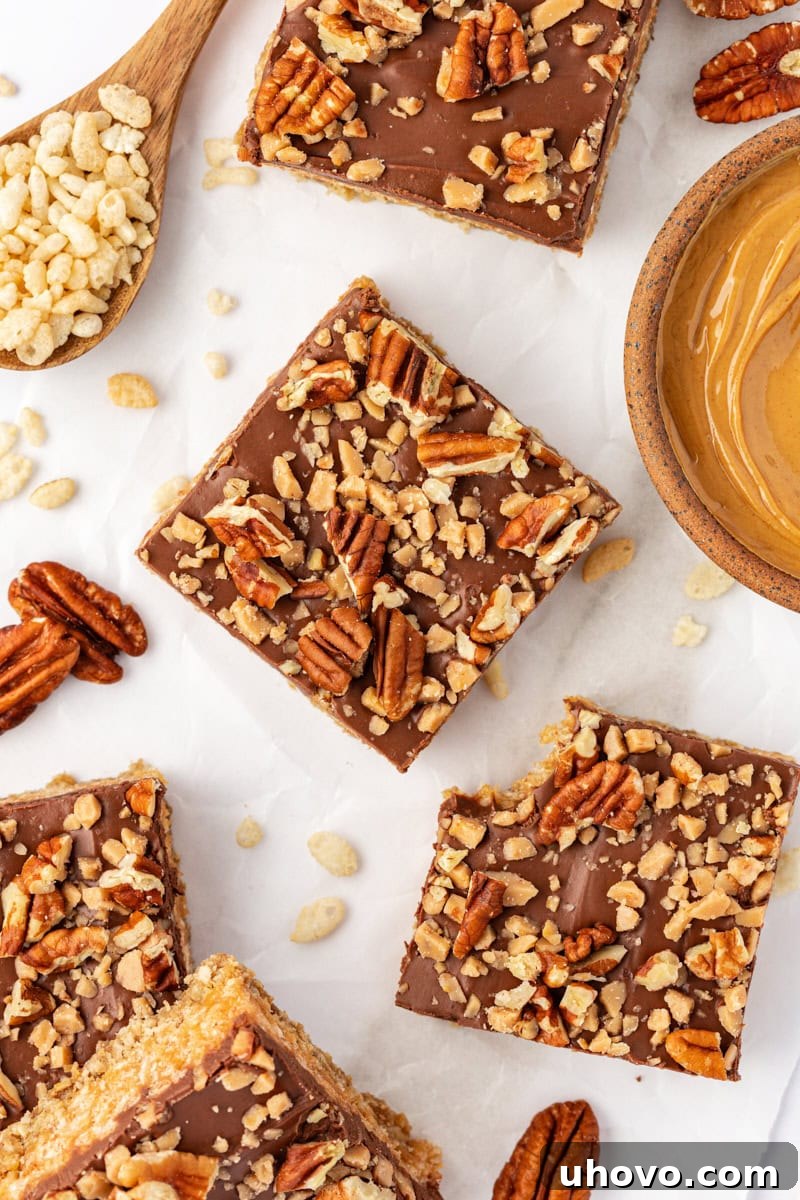 An overhead view of several perfectly cut chocolate peanut butter cereal bars arranged neatly on parchment paper, ready for serving or storage.