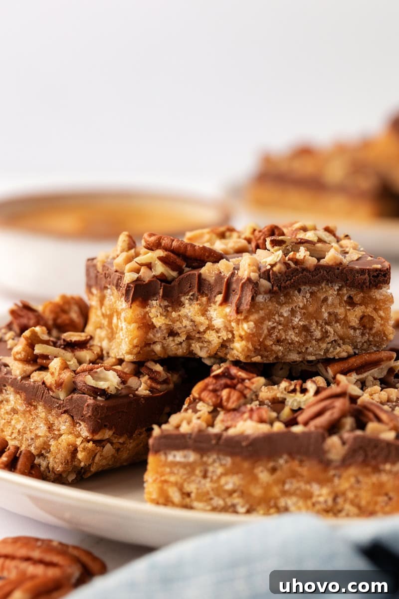 Three stacked chocolate peanut butter cereal bars, with a satisfying bite taken from the top bar, revealing the multiple chewy and crunchy layers.