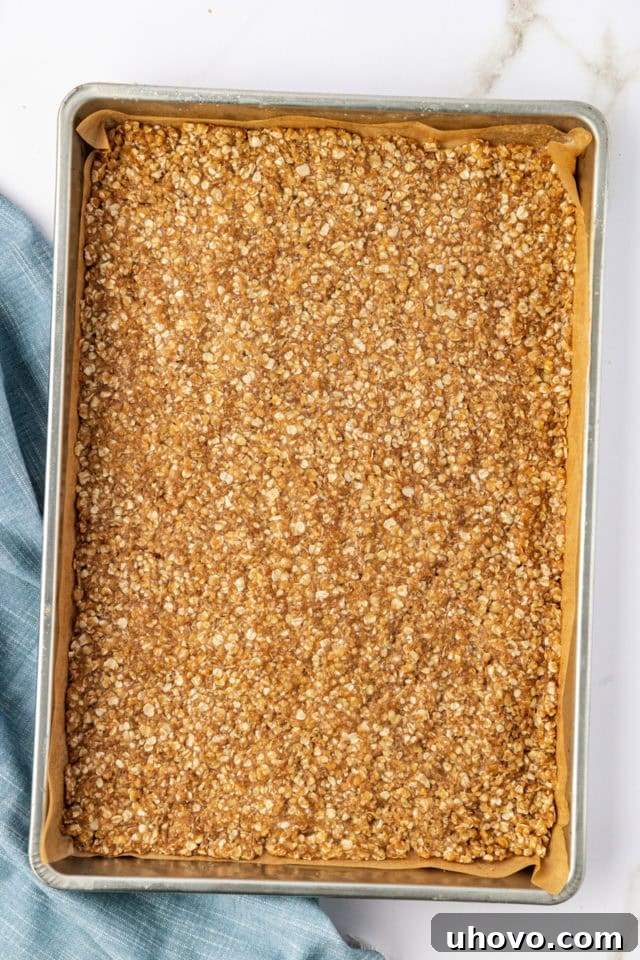 The oat crust mixture evenly spread and pressed into a 15x10 inch jelly roll pan, ready for baking.