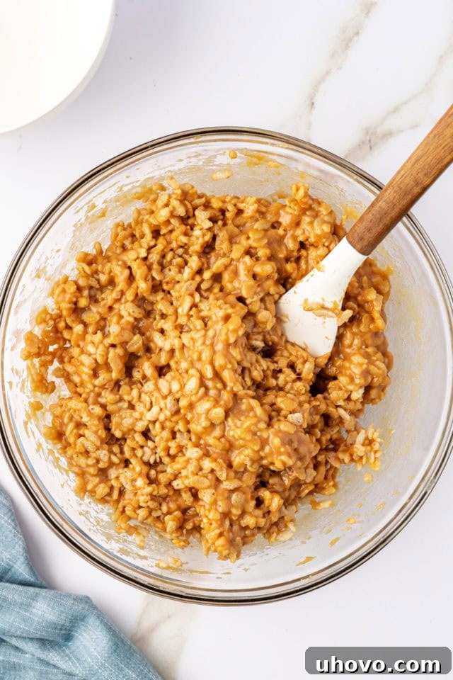 The peanut butter filling mixture, with crisp rice cereal thoroughly stirred in, showcasing its crunchy and sticky texture.