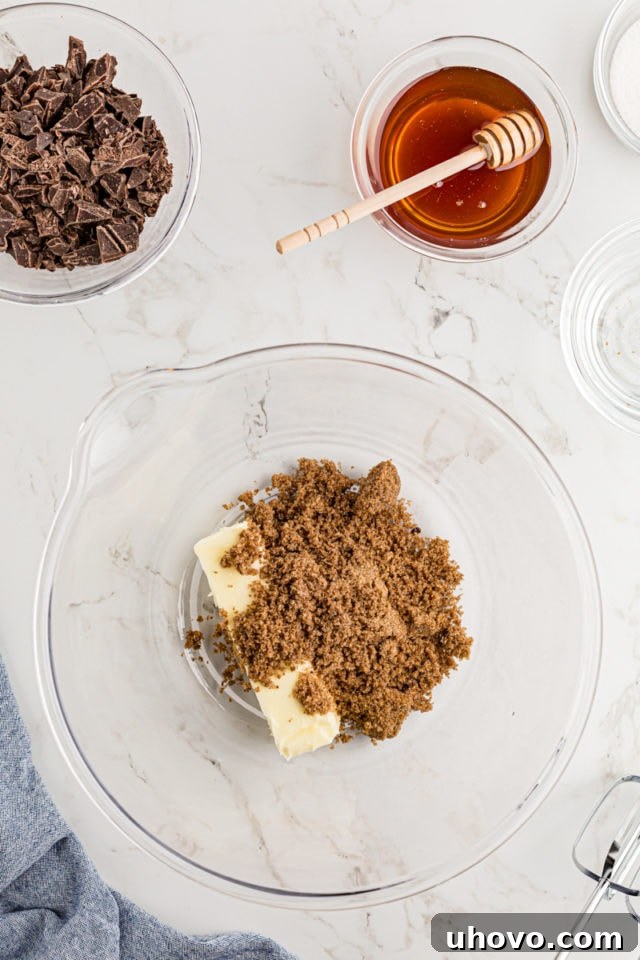 Overhead view of softened butter and dark brown sugar in a mixing bowl, ready to be creamed
