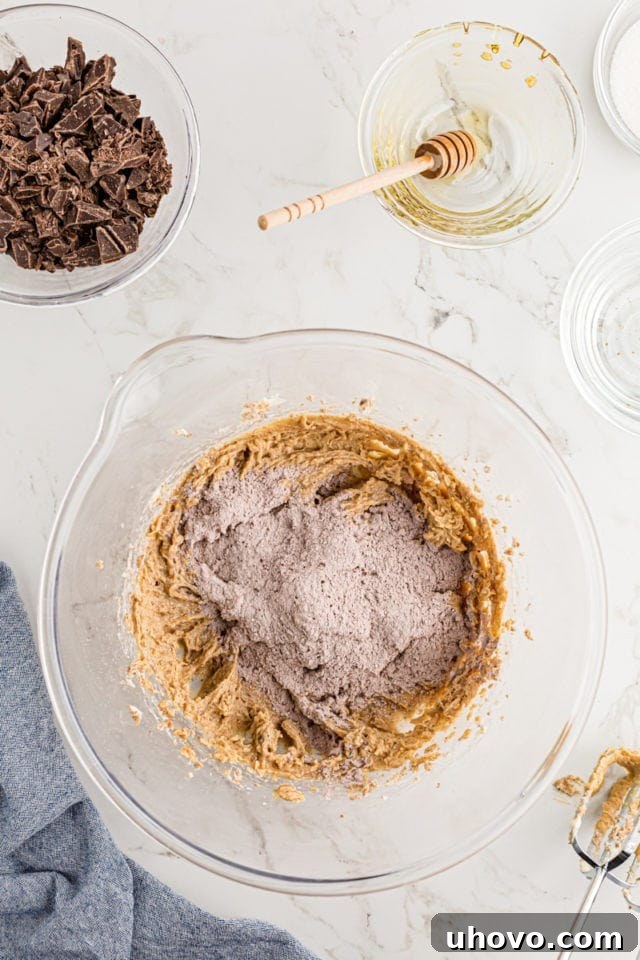 Overhead view of dry ingredients being added to the bowl of creamed wet cookie ingredients