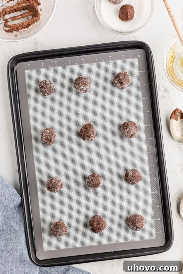 Double Chocolate Brownie Cookie dough balls spaced on a baking sheet, coated in sugar, ready for the oven