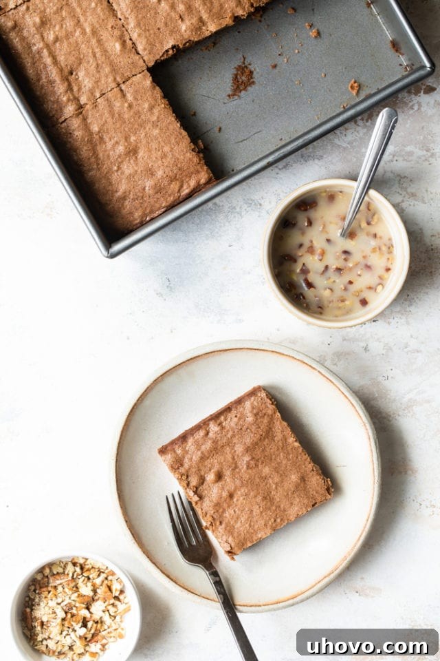An overhead view of a baked German chocolate cake in a square pan, pre-cut into generous slices, awaiting its warm coconut-pecan sauce topping.