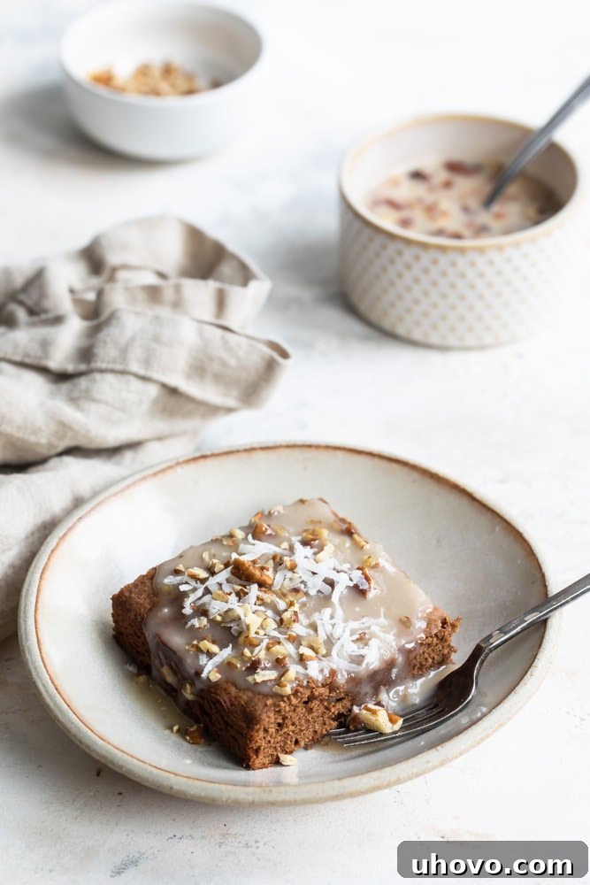 A tantalizing closeup of a German chocolate cake slice, generously adorned with shredded coconut flakes, resting on a beige plate.