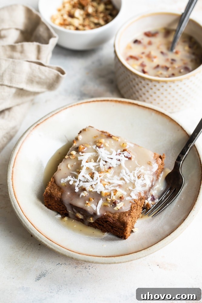 slice of German Chocolate Cake on a beige plate with the warm coconut-pecan sauce poured over it