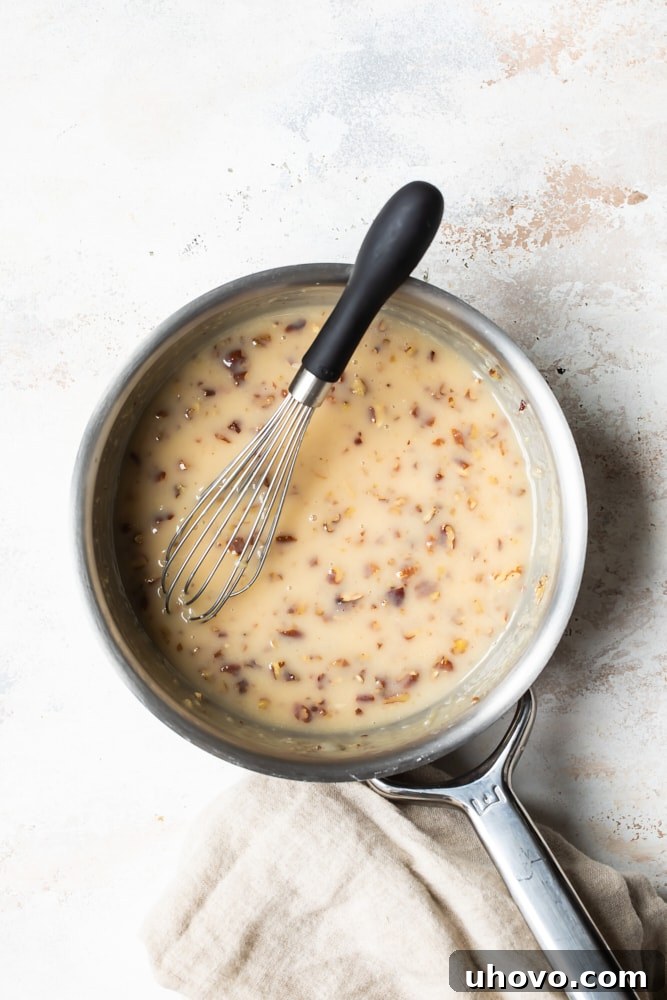 A rich, thick coconut-pecan sauce bubbling gently in a saucepan on the stove, ready to be served.
