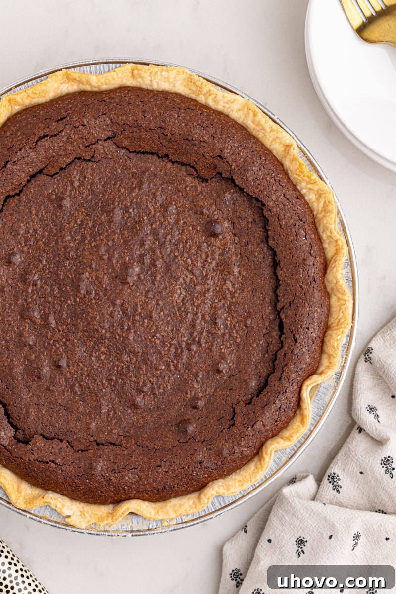 overhead view of a freshly baked hot fudge pie in a pie pan, with a slightly cracked top and rich dark color