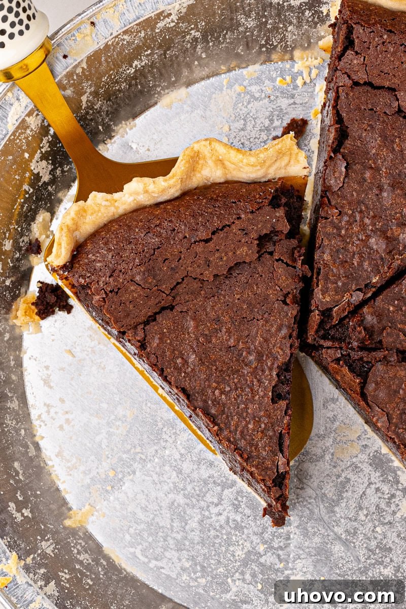 a perfect slice of hot fudge pie sitting on a pie server, showcasing its rich, dark filling and flaky crust