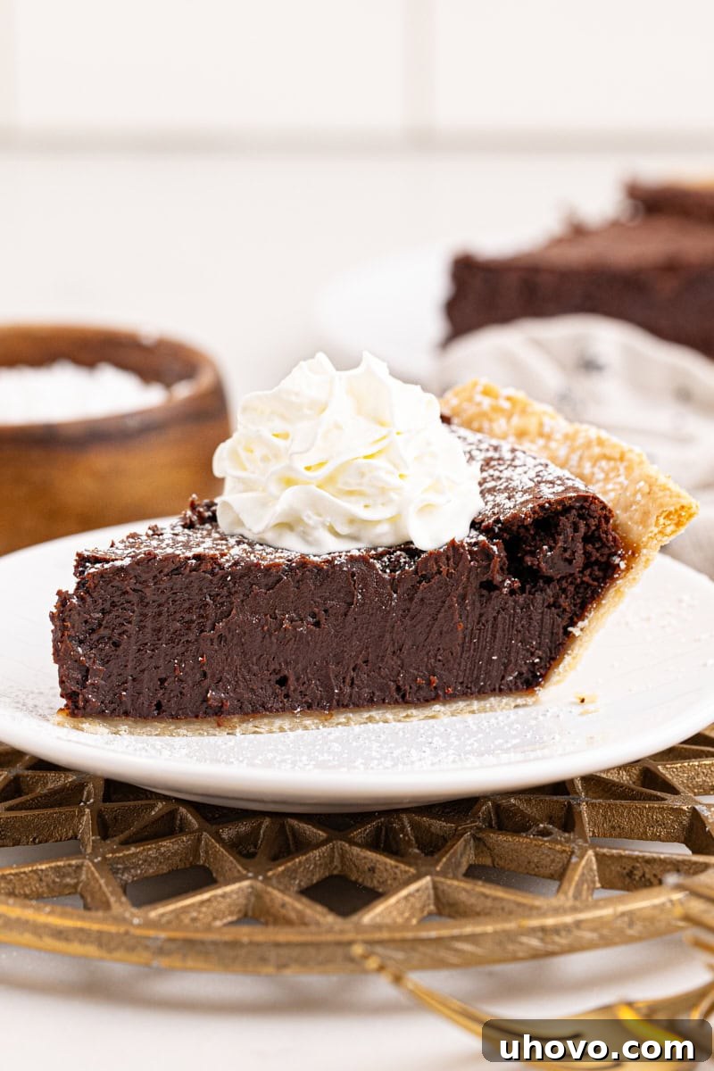 a decadent slice of hot fudge pie topped with a generous swirl of whipped cream, on a plate ready to serve
