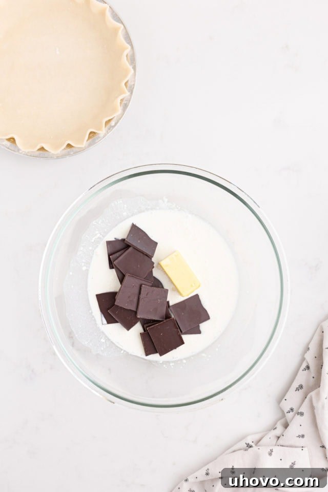overhead view of bittersweet chocolate chunks, unsalted butter cubes, and half-and-half in a heatproof mixing bowl