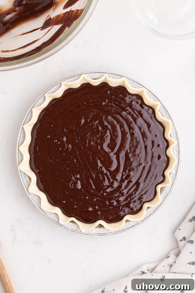 overhead view of an unbaked hot fudge pie, with the rich chocolate filling poured into the pie crust, ready to go into the oven