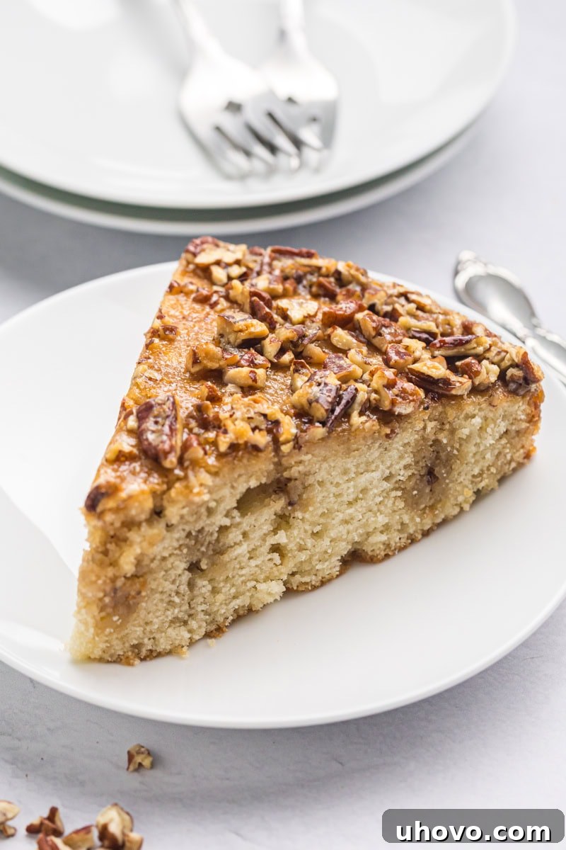 A pristine, artfully cut slice of Pecan Pie Coffee Cake resting on a simple white plate, ready to be enjoyed.