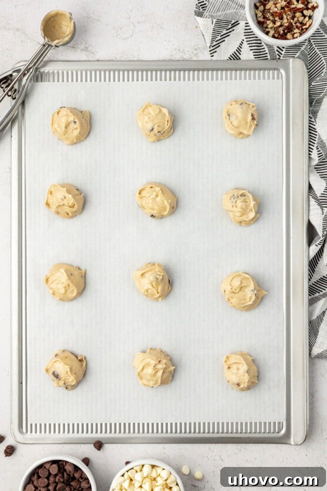 Overhead view of black and white chocolate chip cookie dough on parchment-lined baking sheet