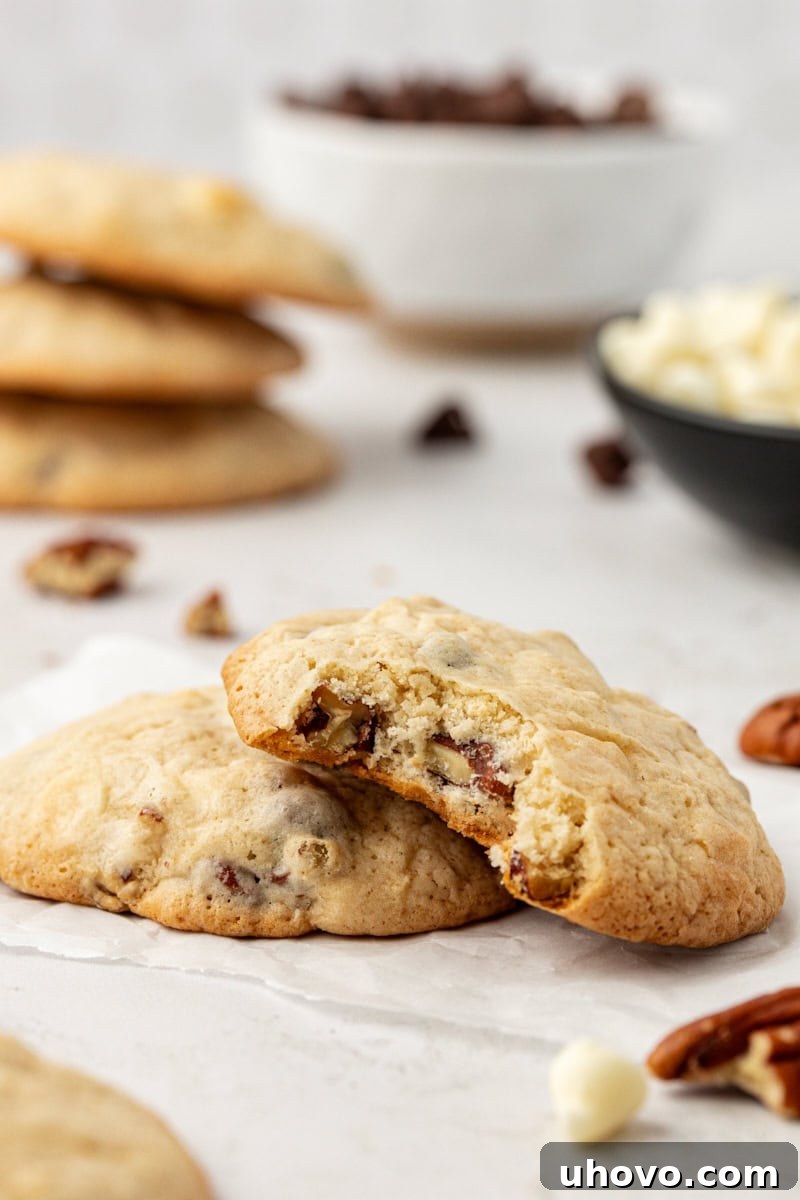 Two black and white chocolate chip cookies with top cookie bitten to show light crumb