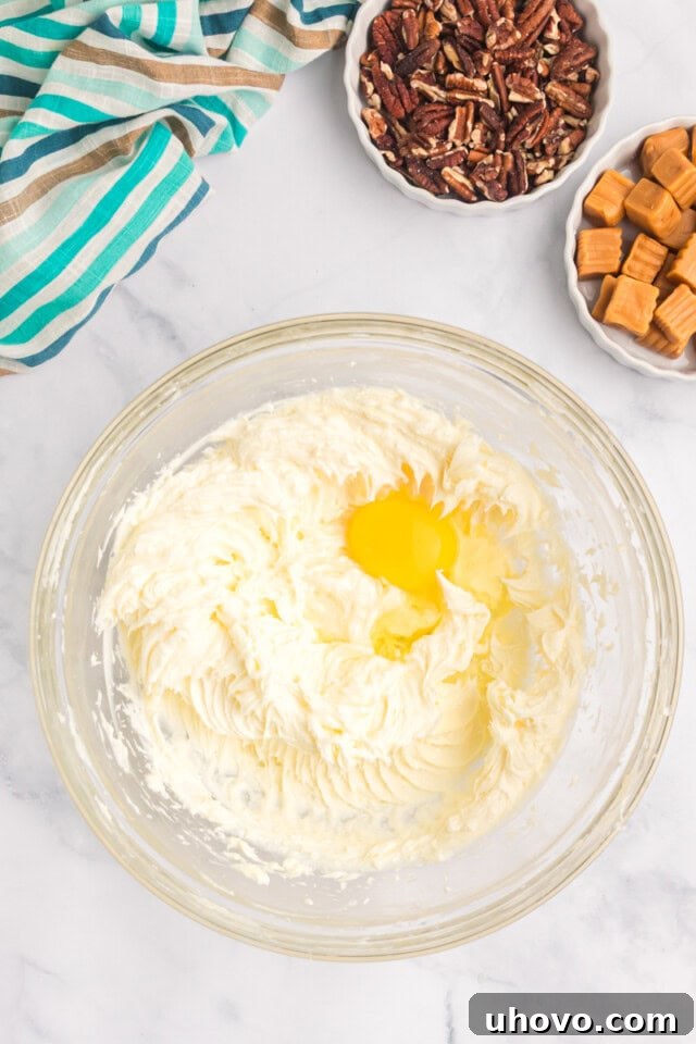 overhead view of egg added to cream cheese mixture for cheesecake filling