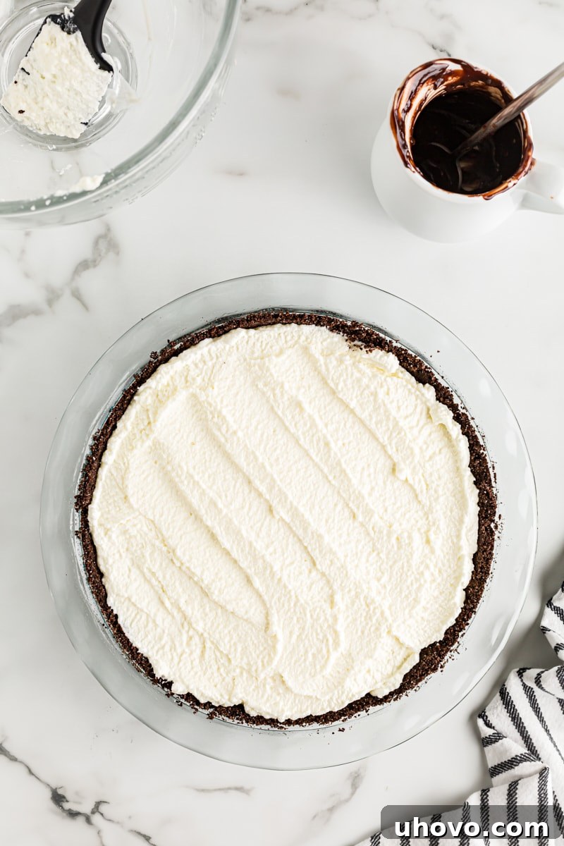 Overhead view of the Chocolate Hazelnut Black-Bottom Pie with whipped cream spread over the ganache, prior to the final chocolate drizzle.