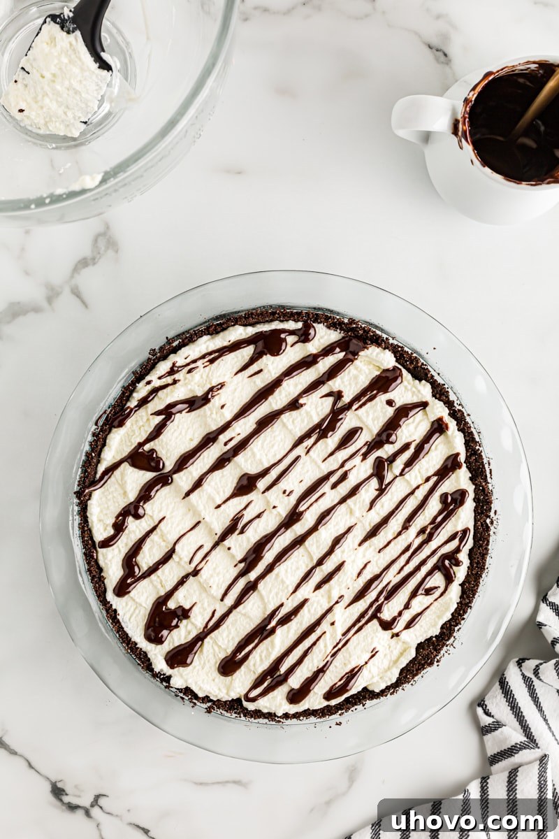 Overhead view of the finished Chocolate Hazelnut Black-Bottom Pie, beautifully garnished with a chocolate drizzle over the whipped cream.