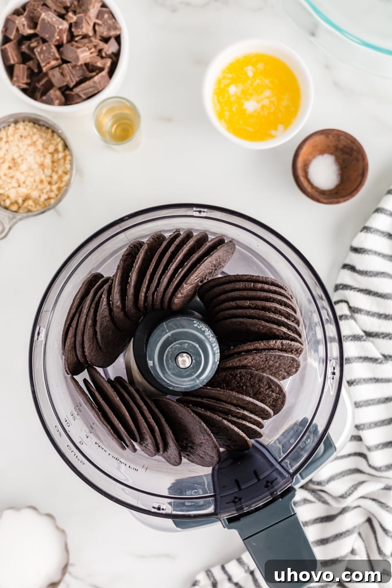 Chocolate wafers being finely ground in a food processor, creating a base for the pie crust.