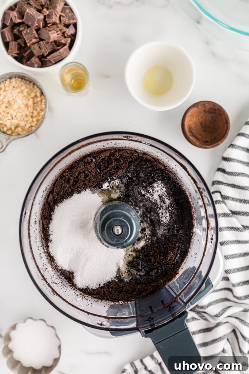 The chocolate pie crust ingredients, including crushed wafers, sugar, salt, and melted butter, being pulsed together in a food processor.