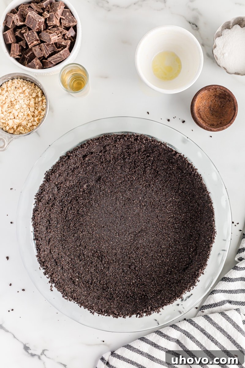 A freshly baked and cooled chocolate cookie pie crust resting in a glass pie plate, ready for filling.