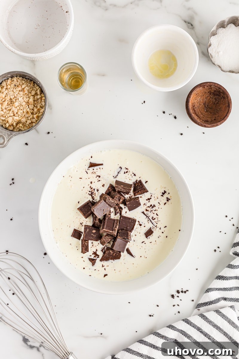 Overhead view of chopped chocolate pieces and hot heavy cream in a bowl, ready to be combined for ganache.