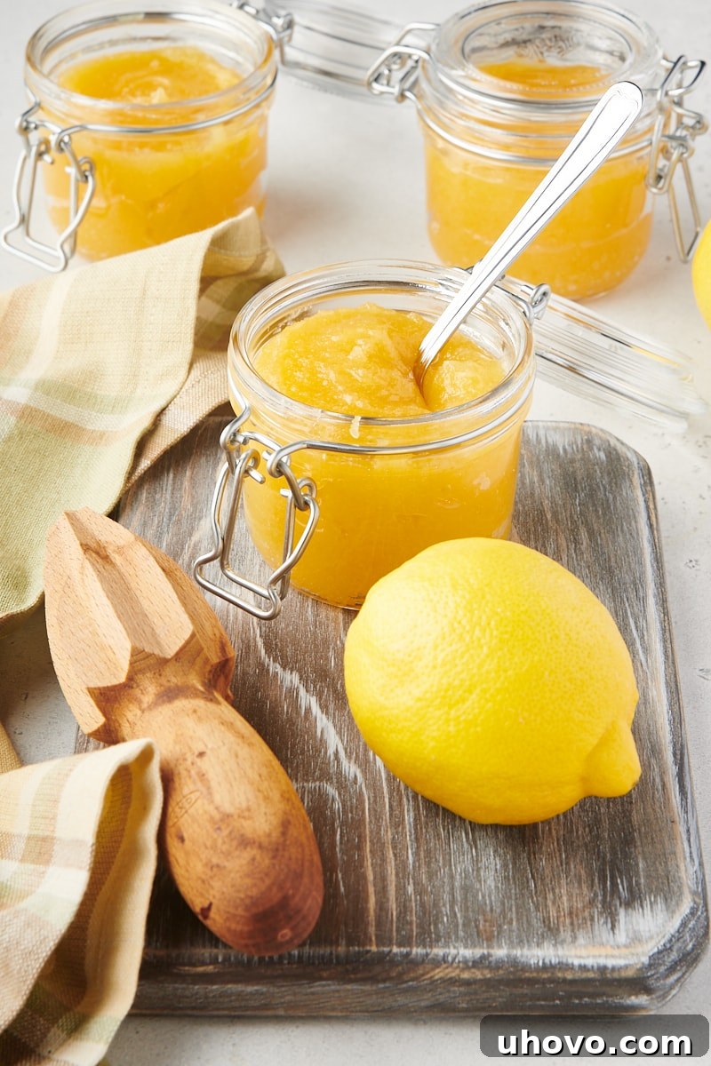 a glass jar of lemon curd on a wooden cutting board with a lemon and citrus juicer