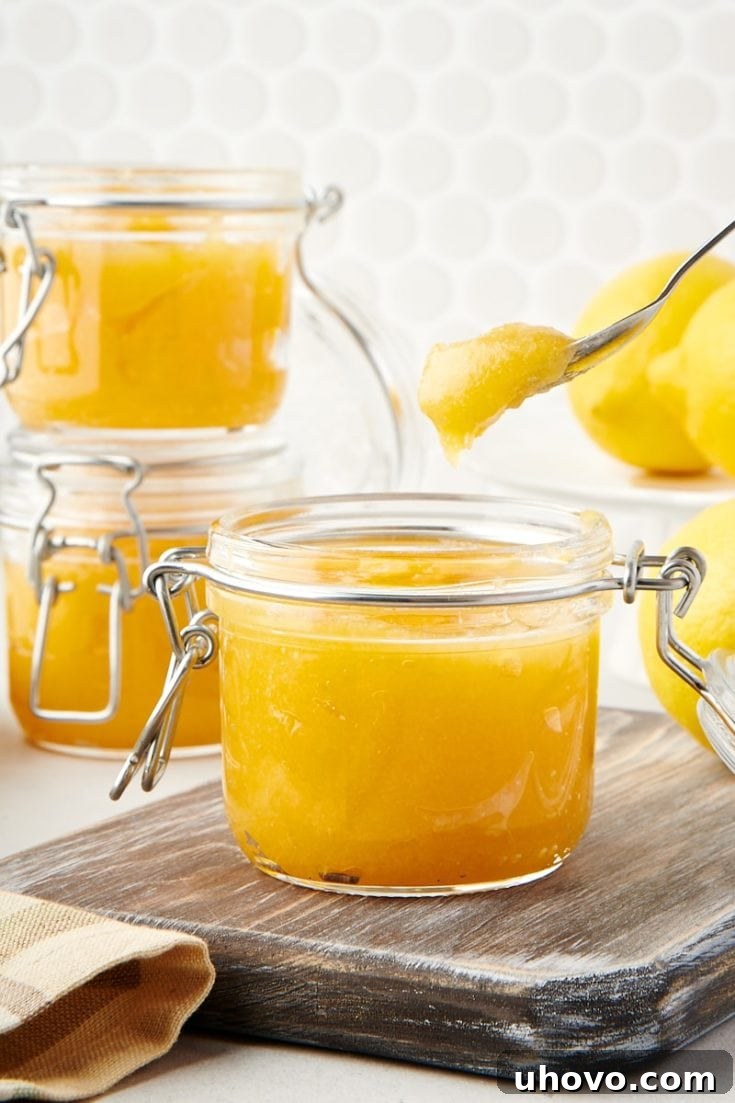 lemon curd in a glass jar with a spoonful above