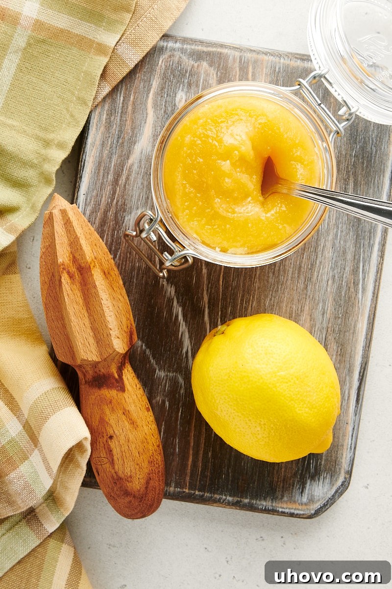 overhead view of an opened jar of lemon curd on a wooden cutting board