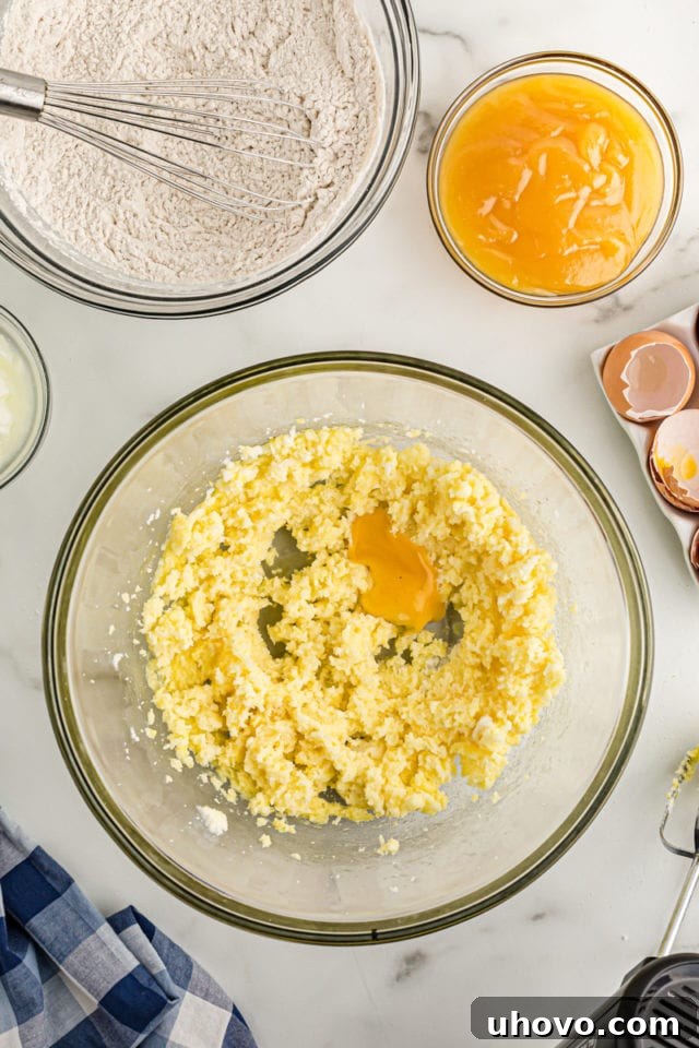 Overhead view of egg yolk in bowl with creamed butter and sugar