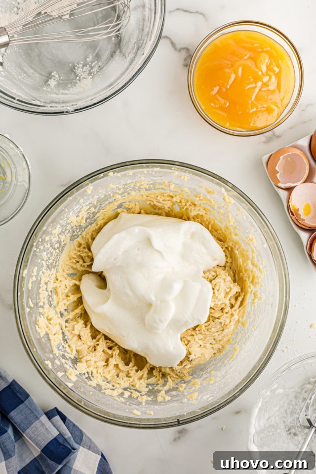 Overhead view of egg whites added to bowl of cake batter