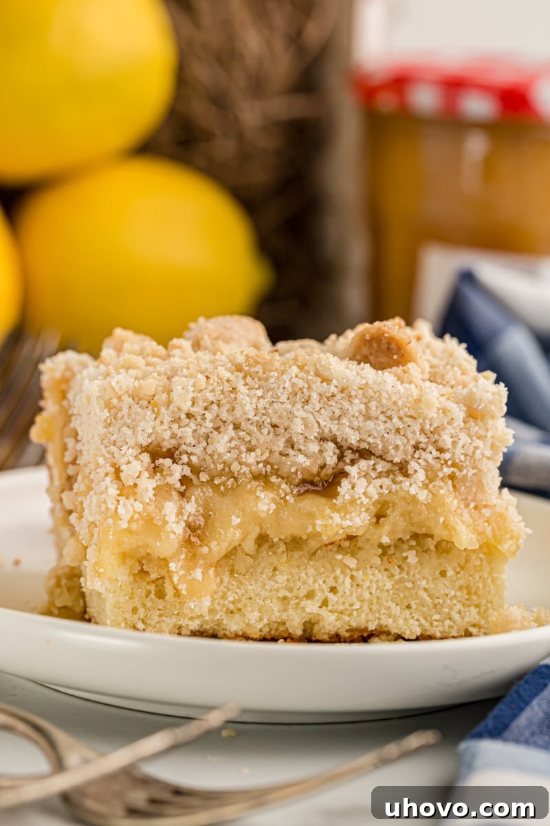 Piece of lemon yogurt crumb cake on plate with lemons in background