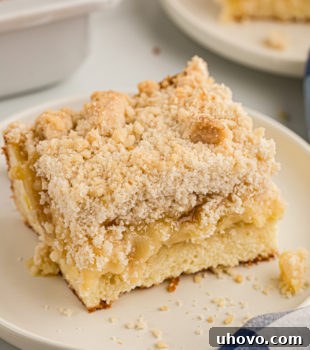 Piece of lemon yogurt crumb cake on plate, with another plate of cake in background