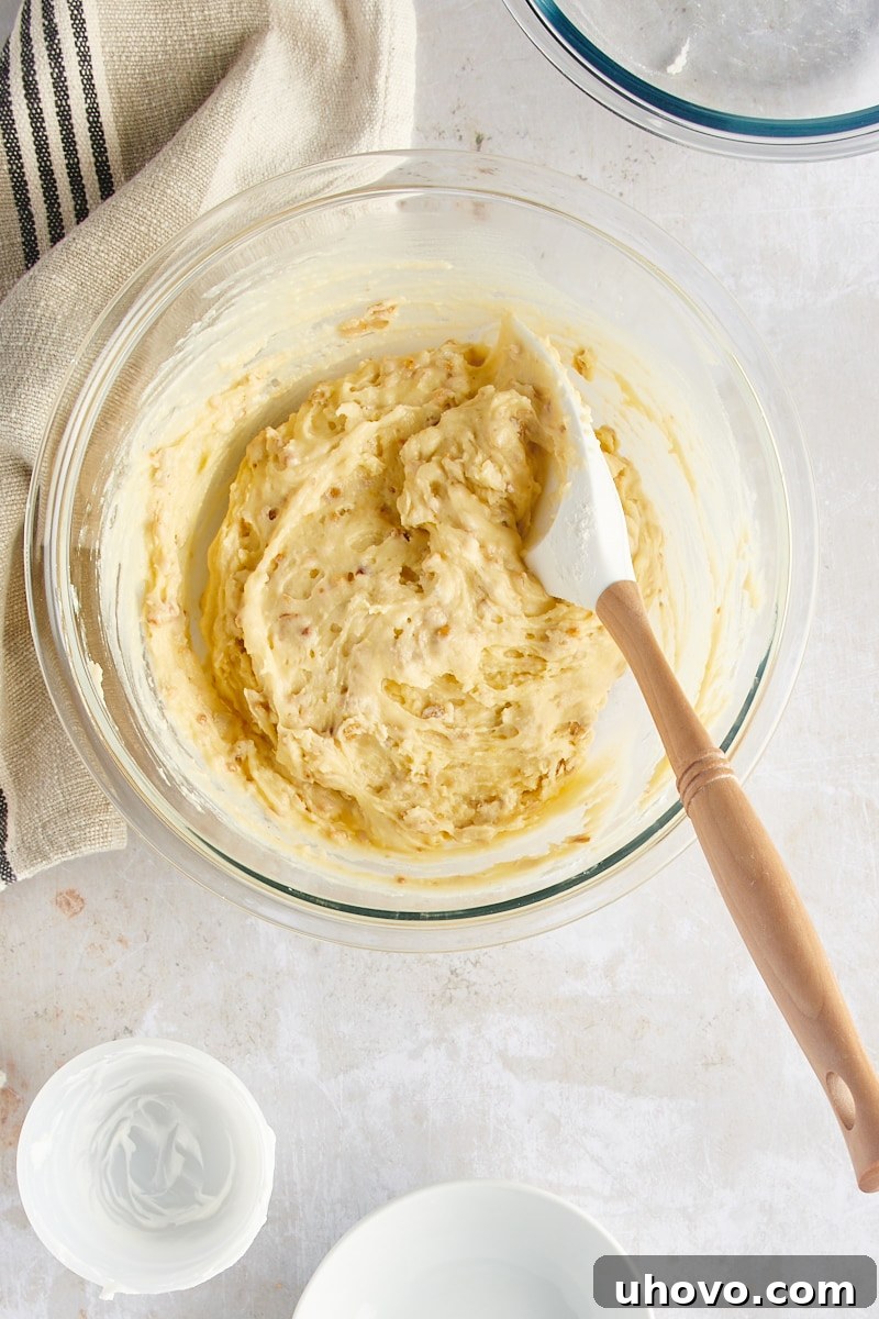 Overhead view of the fully mixed muffin batter resting in a clear glass mixing bowl, showcasing its smooth consistency.