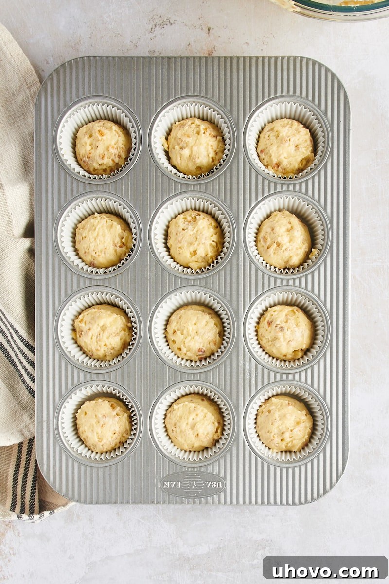 Overhead view of muffin batter expertly scooped into each of the 12 muffin cups in a pan, ready for baking.