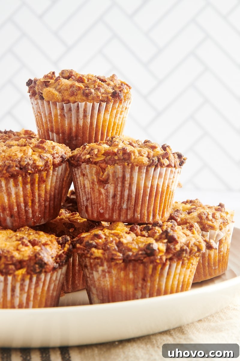 A stack of golden-brown granola yogurt muffins on a decorative platter, showcasing their appealing streusel topping.