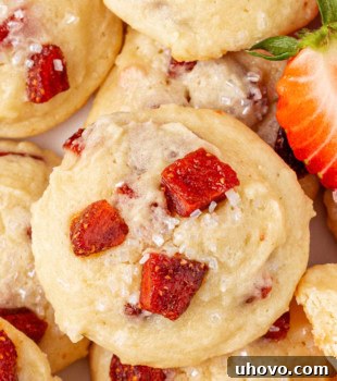 Overhead close-up view of several strawberry cream cheese cookies, showing their texture and fruit pieces.