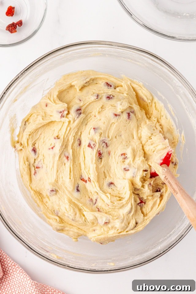 Overhead view of the fully mixed strawberry cream cheese cookie dough in a glass mixing bowl, showcasing its smooth texture.