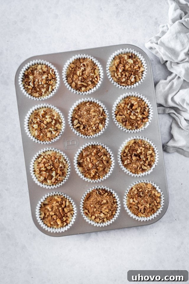 Overhead view of Sour Cream Coffee Cake Muffins in a muffin pan, generously topped and ready to be baked to golden perfection.