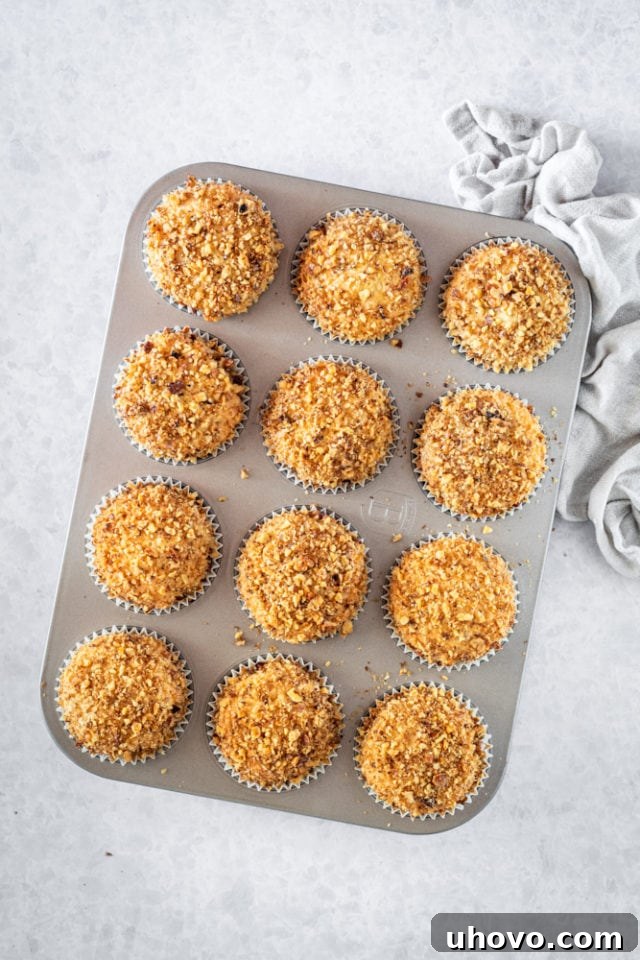 Overhead view of a dozen freshly baked Sour Cream Coffee Cake Muffins, golden and inviting, cooling on a wire rack.