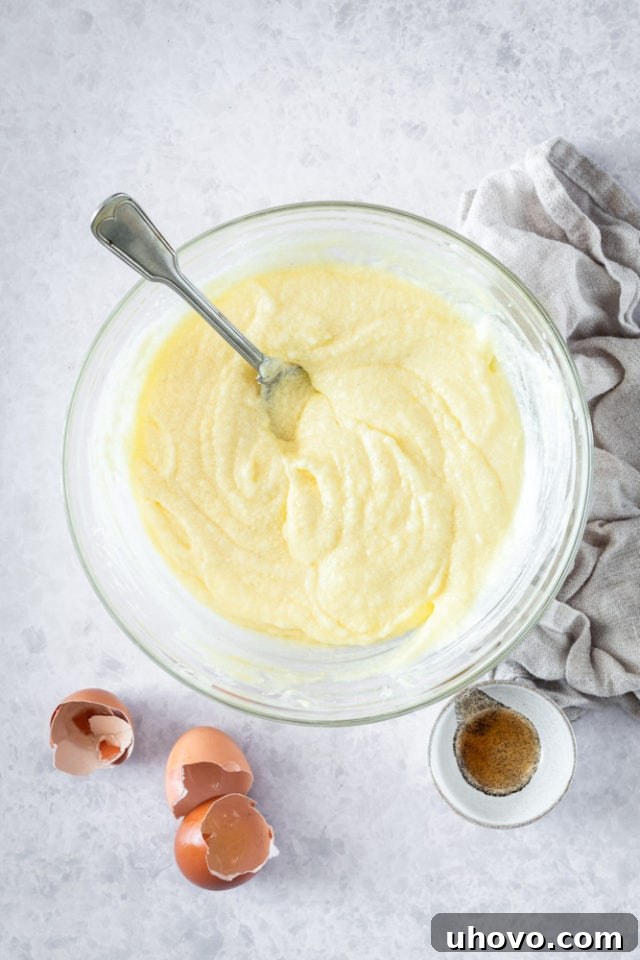Overhead view of the fully mixed wet ingredients for Sour Cream Coffee Cake Muffins, a smooth and rich batter in a glass bowl.