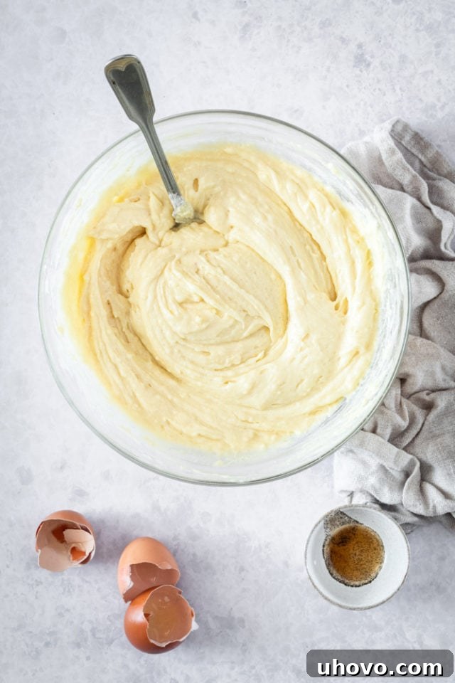 Close-up, overhead view of the thick, perfectly mixed muffin batter in a glass mixing bowl, ready for portioning.