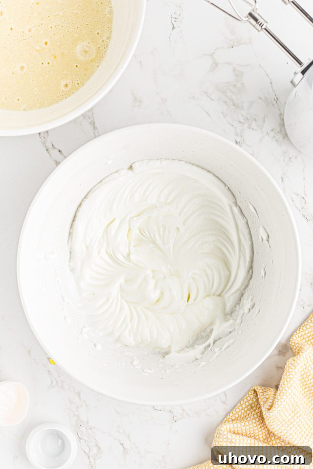 Fluffy, stiffly whipped egg whites in a clean mixing bowl, ready to be folded into the batter.
