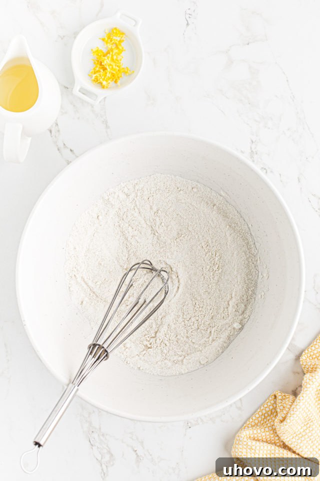Whisking together granulated sugar and all-purpose flour in a large mixing bowl.