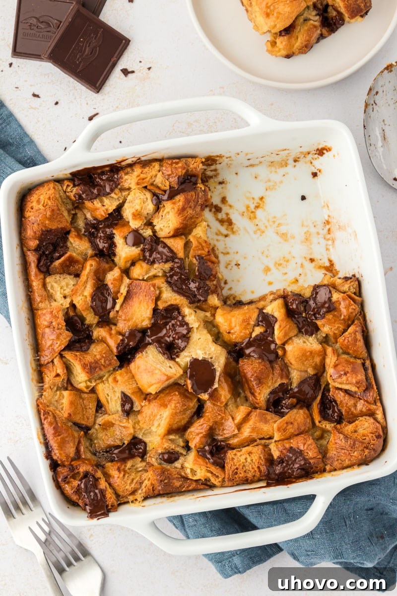 Overhead view of chocolate croissant bread pudding in square baking dish with one portion removed